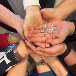 Hände mit Symbolsteinen als Bild für gegenseitige Unterstützung im Team